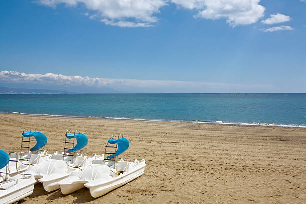 Pedal boats on empty Torremolinos beach, Spain. Pedal boats on empty Torremolinos beach, Costa del sol, Málaga,  Spain. Mediterranean sea, blue sky background, a summer holidays tranquil scene. torremolinos beach stock pictures, royalty-free photos & images