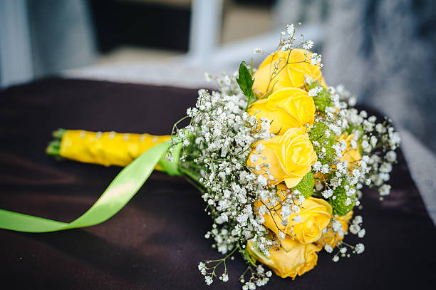 istock Fresh yellow roses with a checkered ribbon on wooden table 473250166