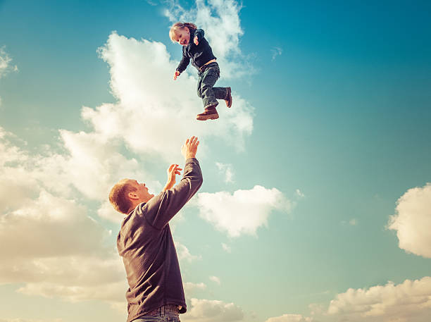 istock Father with raised arms catching young girl falling from sky 473252494