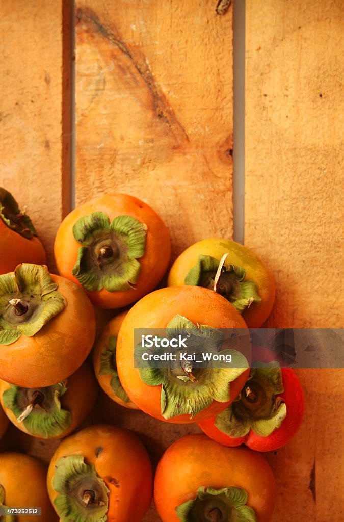 Persimmons Persimmons over wooden box background 2015 Stock Photo
