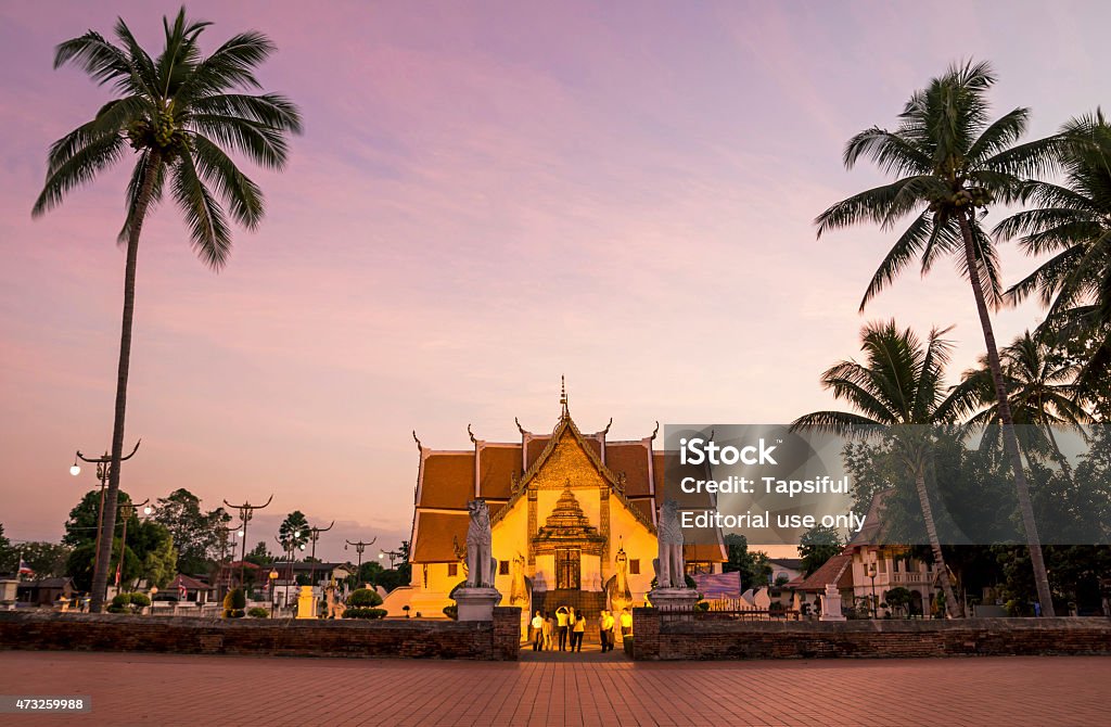 Buddhist temple at sunset in Thailand Nan, Thailand - December 13, 2014: Tourist at the entrance gate of Wat Phumin in Nan, Thailand. The foundation of the temple is dated back to the sixteenth century and it is the mosty visited in the city. Thailand Stock Photo