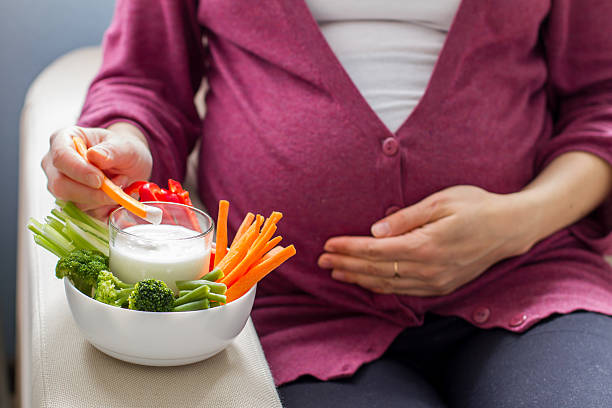Pregnant woman eating vegetable sticks with dip stock photo