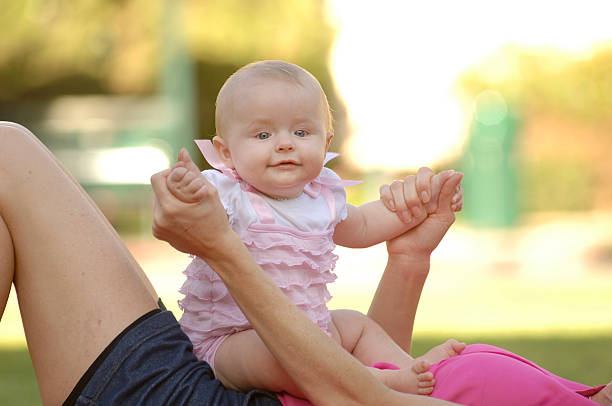 Happy Baby Girl Sitting on Mother's Belly. stock photo