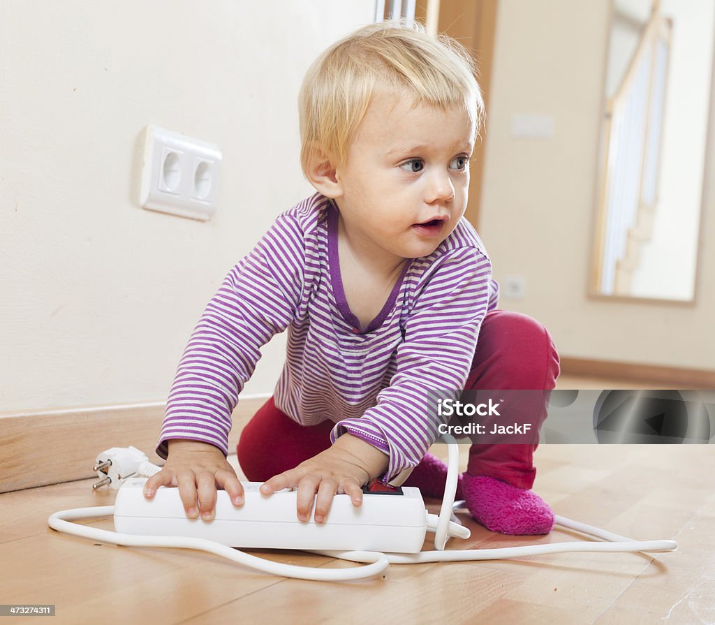 Baby girl playing with electrical extension Baby girl playing with electrical extension  on floor at home 12-17 Months Stock Photo