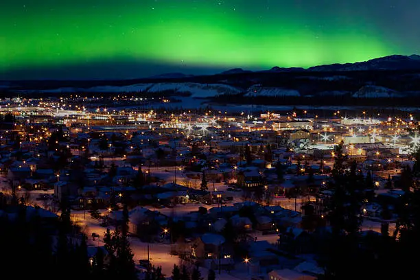 Strong northern lights (Aurora borealis) substorm on night sky over downtown Whitehorse, capital of the Yukon Territory, Canada, in winter.