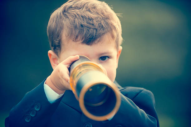 istock Young boy in a business suit with telescope. 473284380