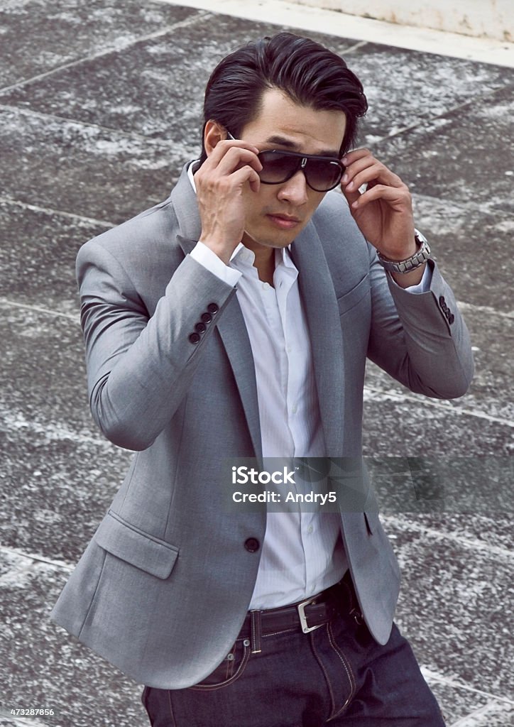 Handsome young Chinese in suit Portrait of handsome young Chinese man wearing stylishly silver suit, white shirt and jeans. Walking and fixing his sunglasses. 2015 Stock Photo