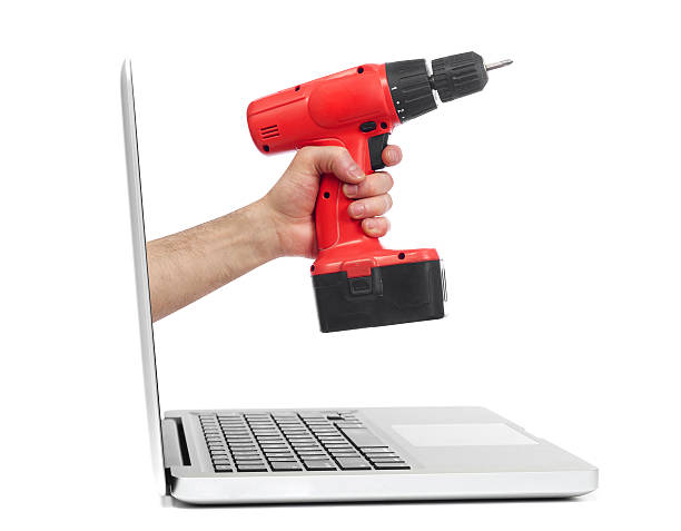 istock Hand with drill out of laptop 473292894