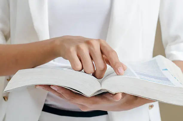 closeup of woman’s hands skimming through a dictionary 