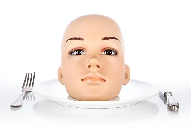 Head of a plastic mannequin lying on a plate. White background