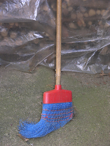 Old and nagged blue plastik broom with wooden stick