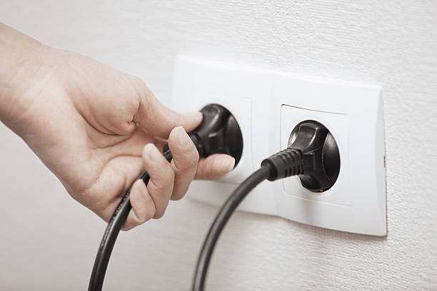 istock Close up of a hand pushing a plug into an electric socket 473295522