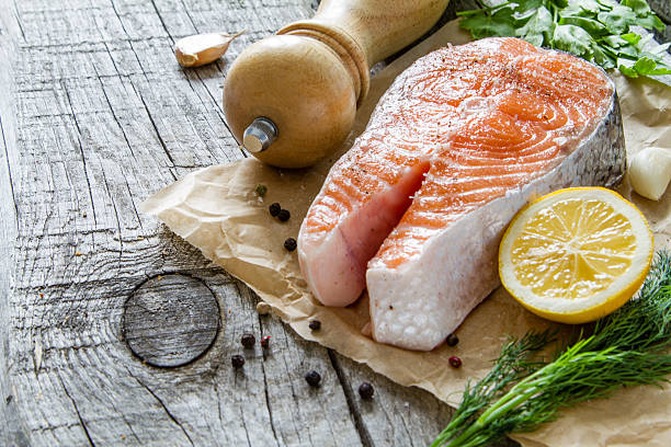 istock Salmon steak with pepper, dill, lemon, garlic on baking paper 473297464