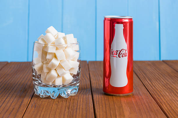 Kiev, Ukraine May 8, 2015: Coca-Cola and glass with sugar Kiev, Ukraine May 8, 2015: Can of Coca-Cola and transparent glass with cubes of sugar standing on a dark wooden background. coke zero photos stock pictures, royalty-free photos & images