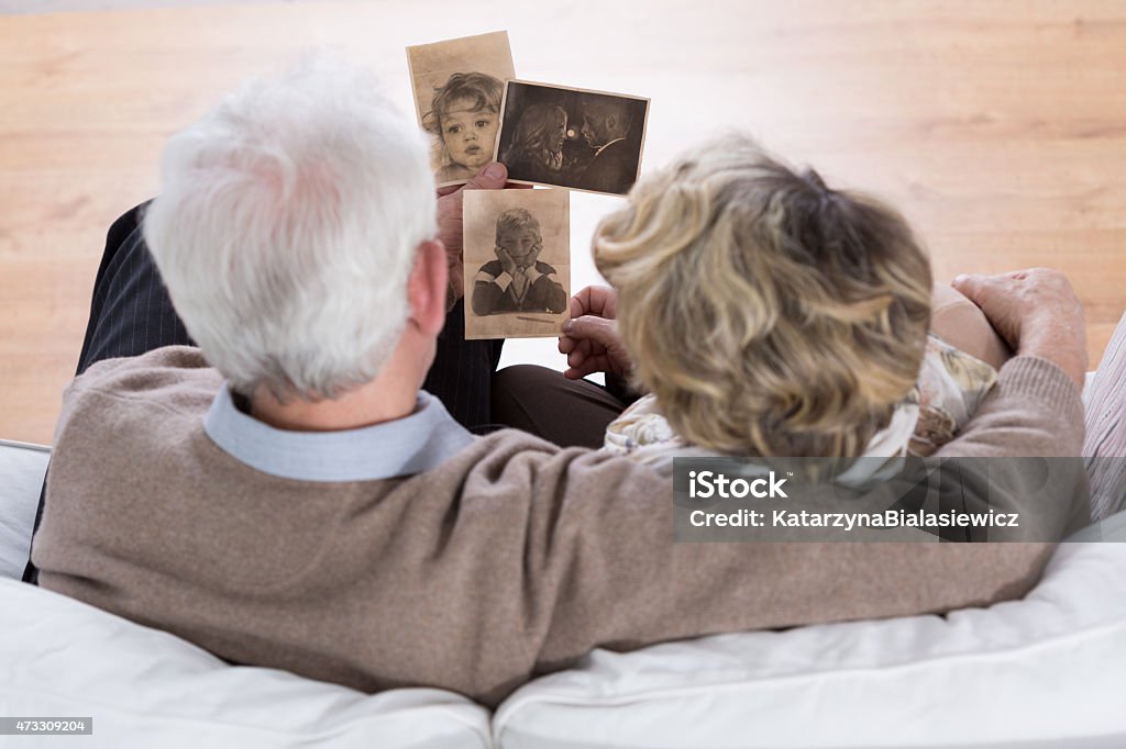 Marriage looking at photos Senior marriage sitting on the sofa and looking at old photos Photograph Stock Photo