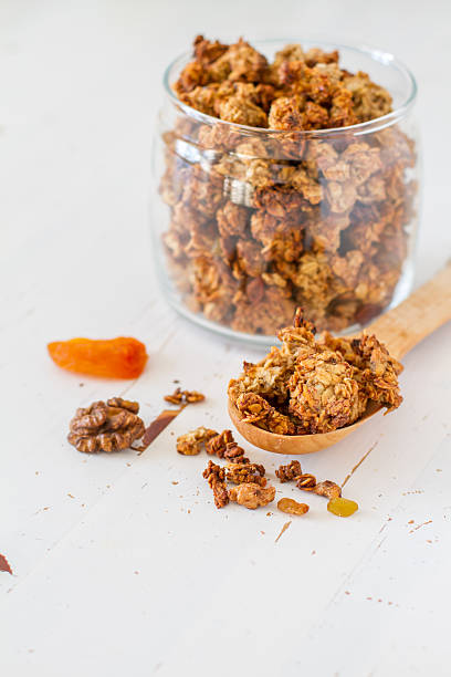 istock Granola in glass jar, spoon, white wood background 473309480