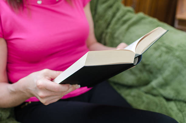 istock Woman reading a book on a couch 473310002