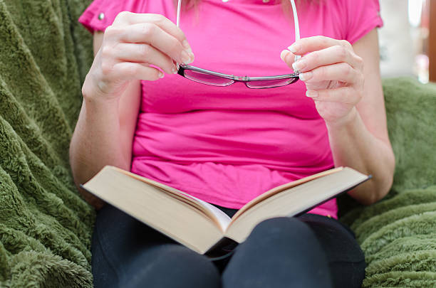 istock Woman reading a book on a couch 473310022