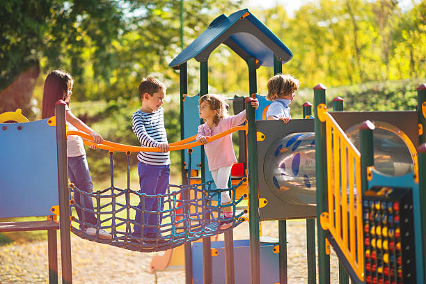Children playing in the park at playground and communicating. Small group of children having good time at jungle gym and talking. playground stock pictures, royalty-free photos & images