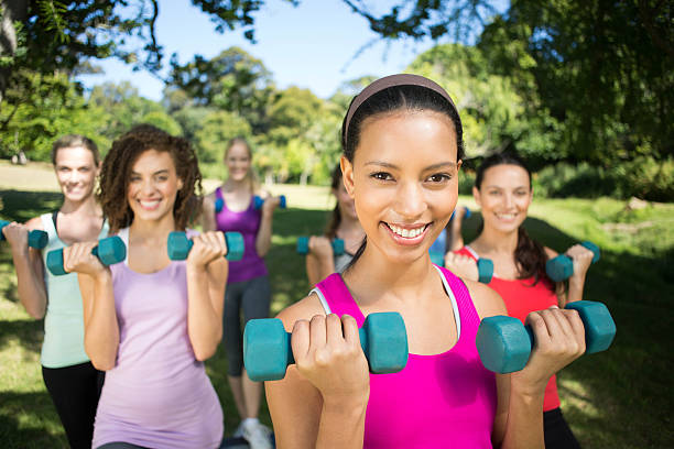 istock Fitness group lifting hand weights in park 473318882