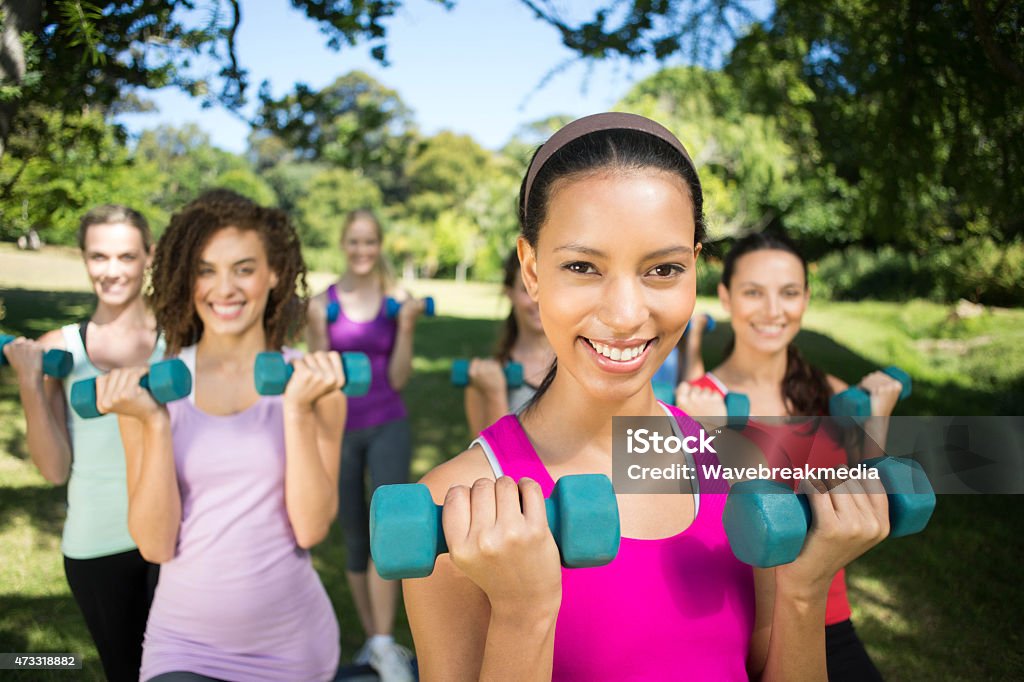 Fitness group lifting hand weights in park Fitness group lifting hand weights in park on a sunny day 20-24 Years Stock Photo