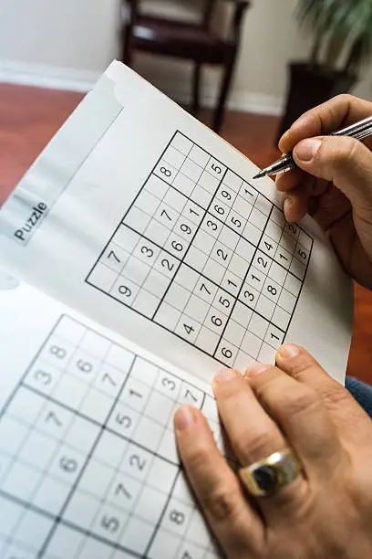 unrecognizable woman holding a pen playing sudoku at her doctors office