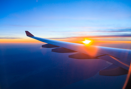 Sunset under aircraft wing skyline view from airplane in flight.