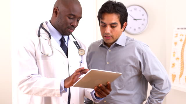 African American doctor using tablet pc with Hispanic patient