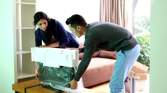 Young couple installing new television in living room