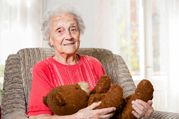 シニア古いブラウン teddybear を持つ女性 - old armchair women senior adult ストックフォトと画像