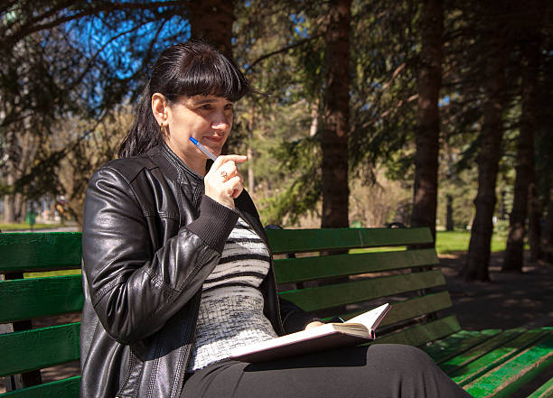 istock beautiful woman sitting on a park bench 473358958