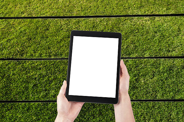 istock hands hold the tablet on a background of grass 473359732