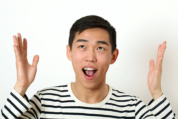 istock Funny young Asian man gesturing with hand and looking upward 473365830