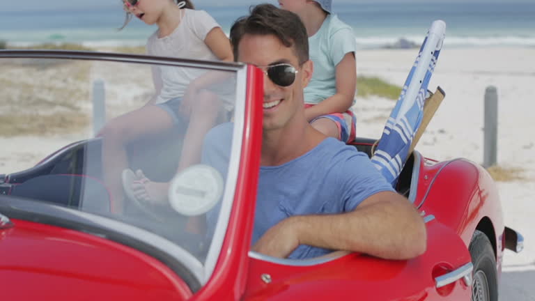 Father and children in convertible at beach