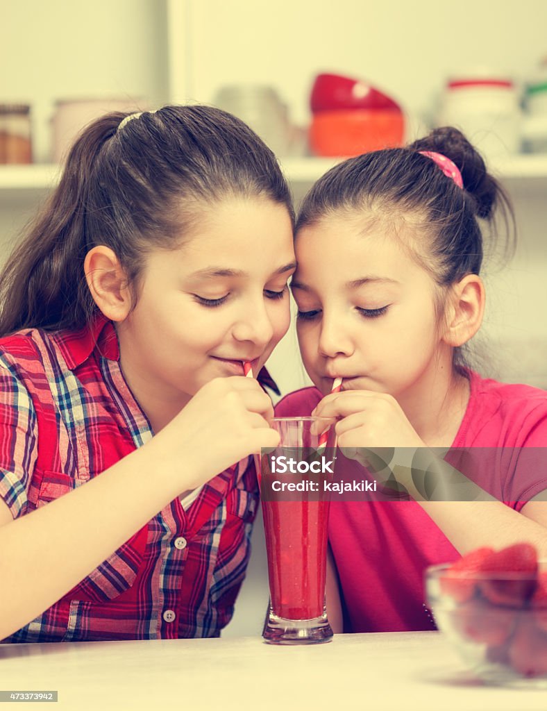 Hermosas chicas bebiendo un poco un batido de fresa - Foto de stock de 10-11 años libre de derechos