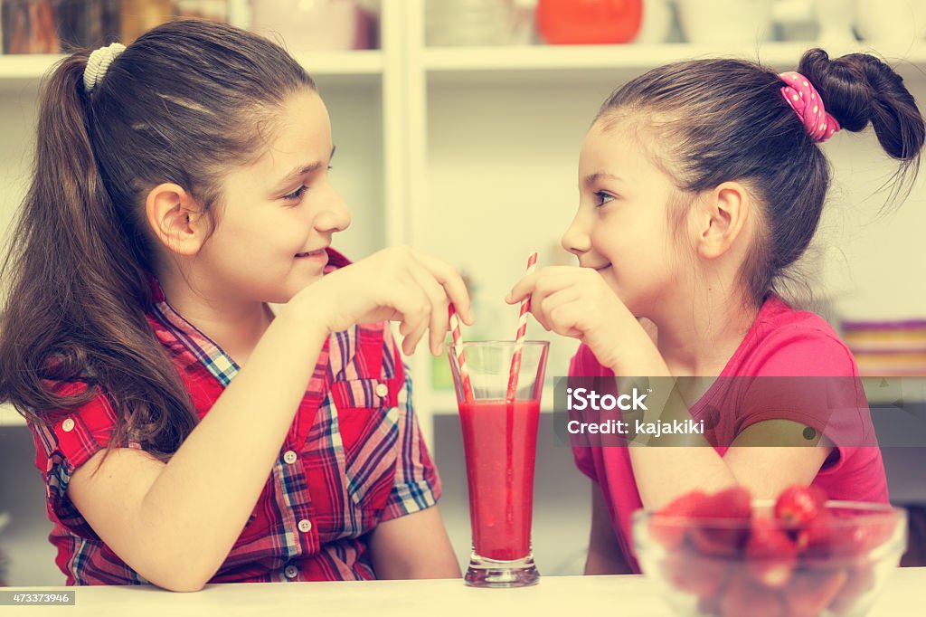 Hermosas chicas bebiendo un poco un batido de fresa - Foto de stock de 10-11 años libre de derechos