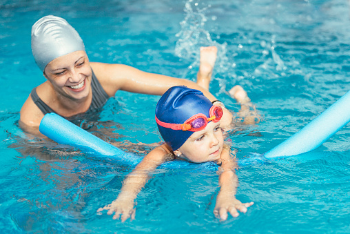 Swimming class - little girl learning to swim with swimming  instructor