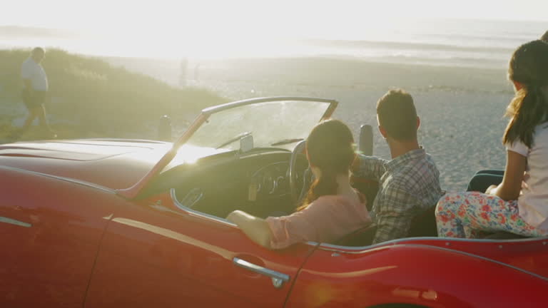 Family sitting in convertible at beach