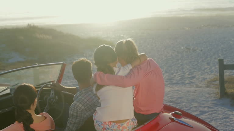 Family sitting in convertible at beach