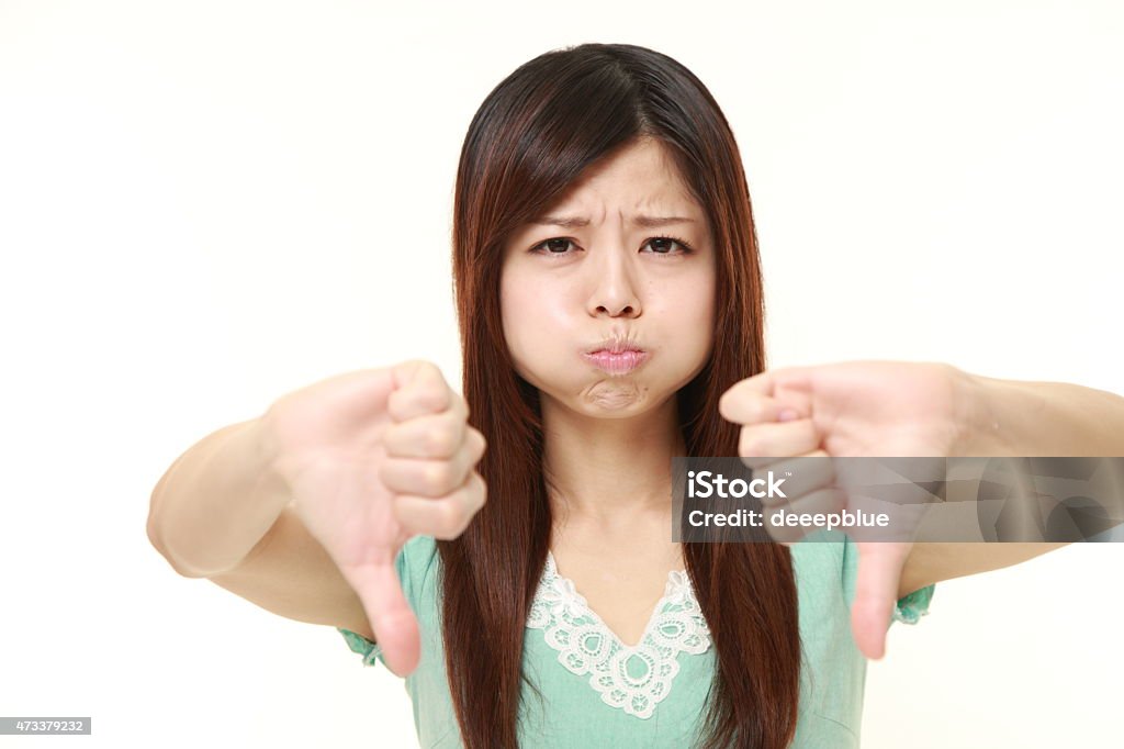 woman with thumbs down gesture portrait of young Japanese woman on white background 2015 Stock Photo