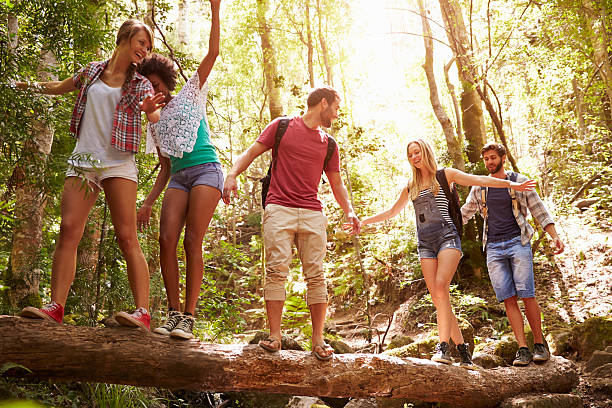 istock Group Of Friends Balancing On Tree Trunk In Forest 473420348
