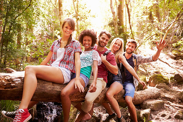 istock Group Of Friends Balancing On Tree Trunk In Forest 473420364