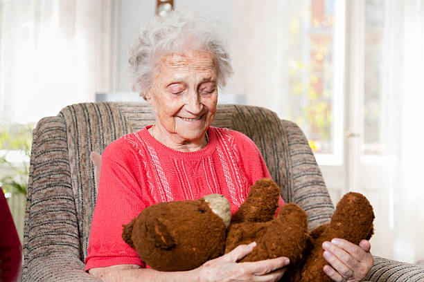 高齢者の女性のシッティングエリアには、アームチェア、古い teddybear - old armchair women senior adult ストックフォトと画像
