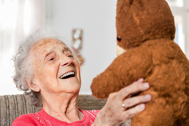 シニア古いブラウン teddybear を持つ女性 - old armchair women senior adult ストックフォトと画像