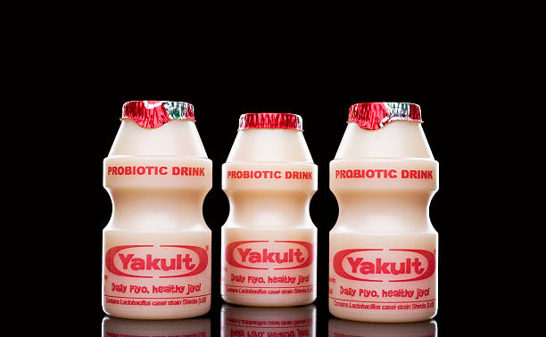 Yakult - Probiotic drink Yakult New Delhi, India - October 31, 2013: Japanese probiotic drink Yakult isolated on a black studio background. singh stock pictures, royalty-free photos & images