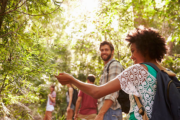 istock Woman touching a plant during her group's countryside walk 473422130
