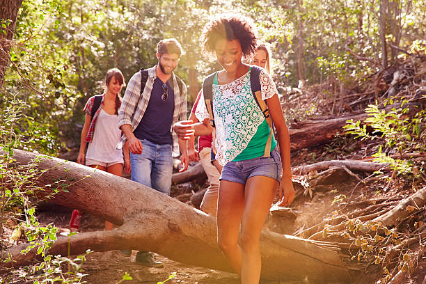 istock Group Of Friends Jumping Over Tree Trunk On Countryside Walk 473422198