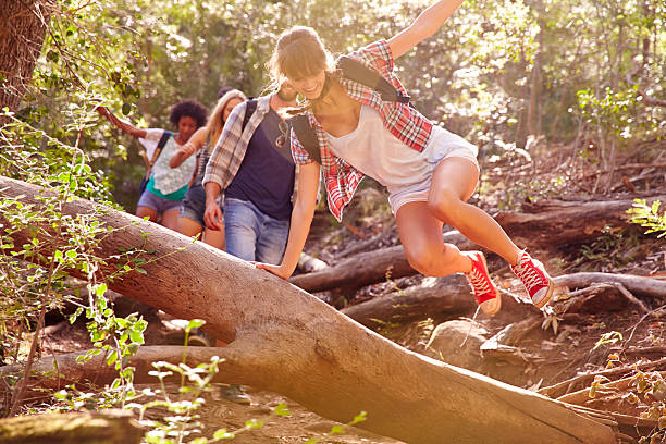 istock A group of people hiking and jumping over a fallen tree 473422214