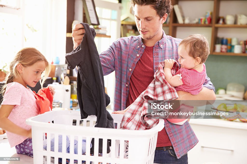 Father And Children Sorting Laundry In Kitchen Laundry Stock Photo