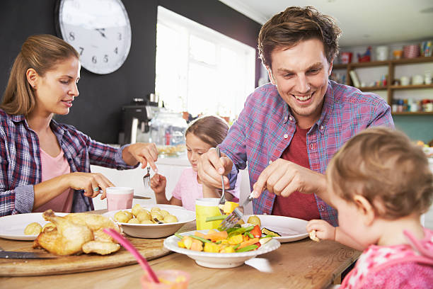 A family eating a meal together in the kitchen Family Eating Meal In Kitchen Together 6 11 months stock pictures, royalty-free photos & images